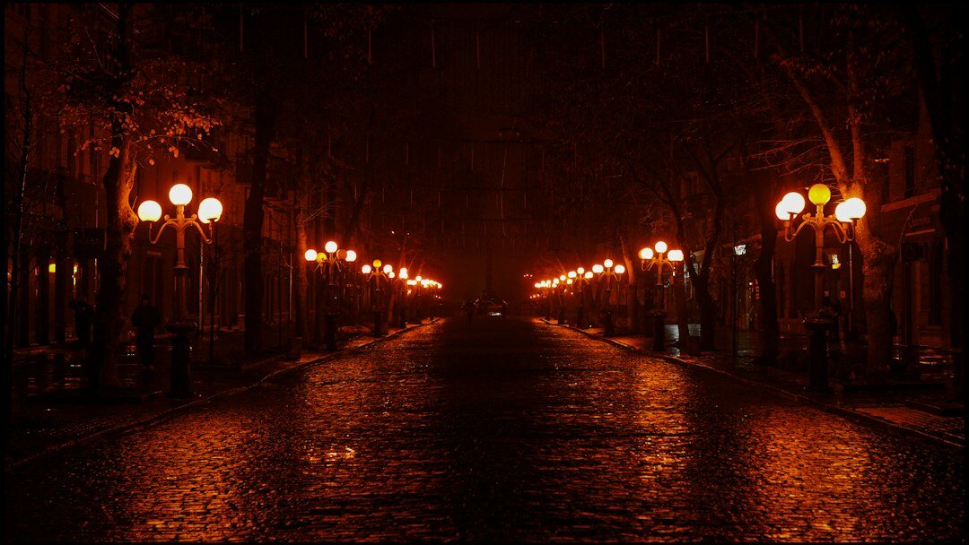 Foggy empty European cobblestone street at night with a lit street lamp
