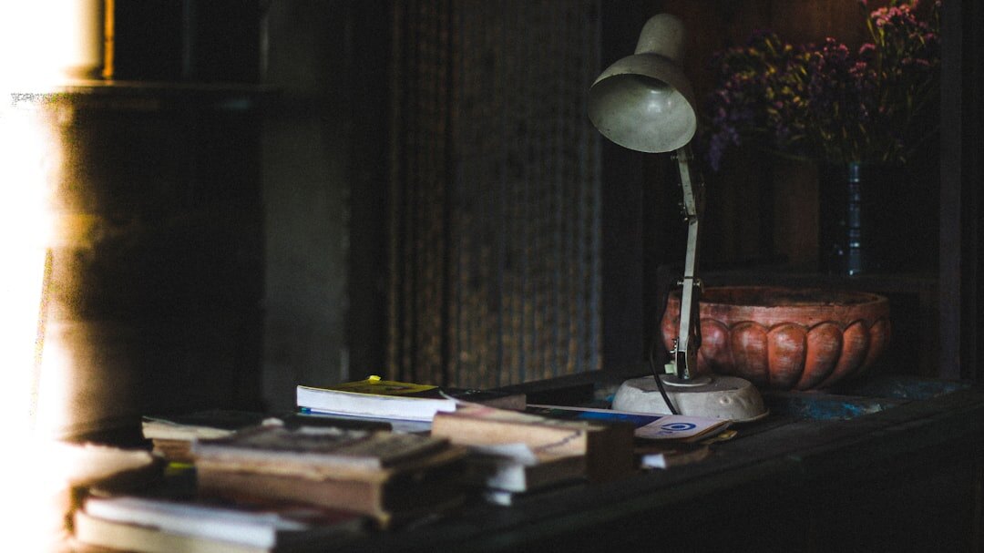 Old wooden writing desk with typewriter and notebook lit by lamp